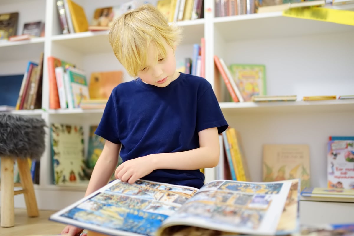 A young reader absorbed in a book among the shelves
